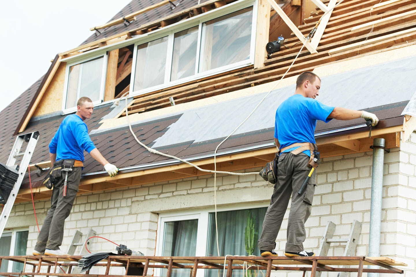 Two construction workers roofing 
 a house