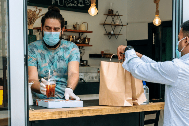 Restaurant employee placing to-go orders at a pickup window for a customer to grab