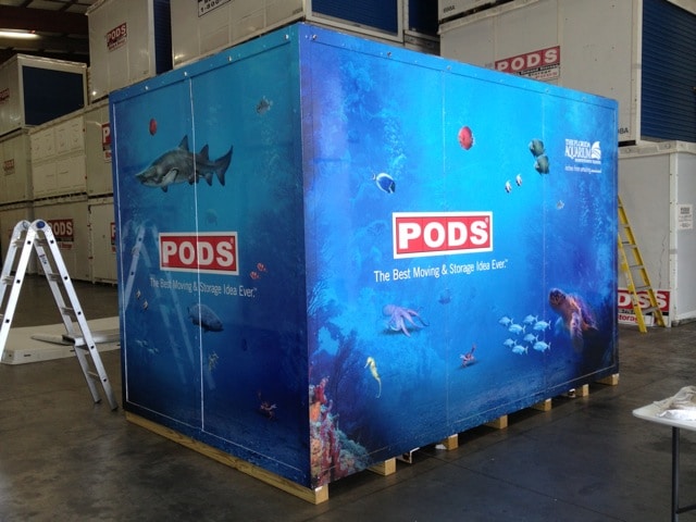 A modified shipping container with a custom aquatic decal wrap