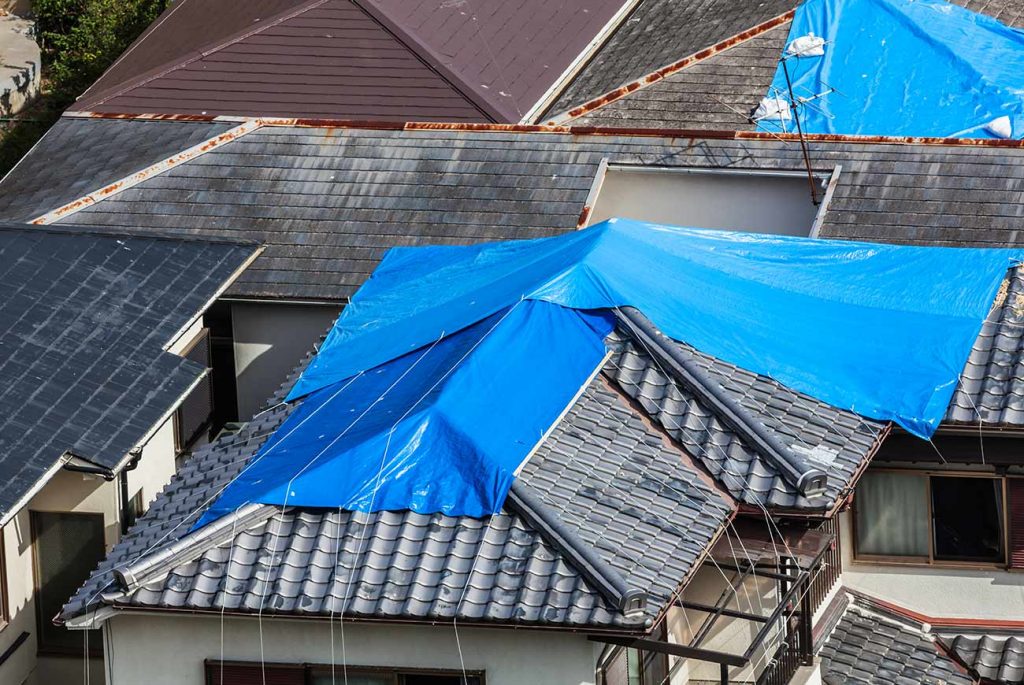 Damaged roofs covered in tarps in an urban neighborhood 