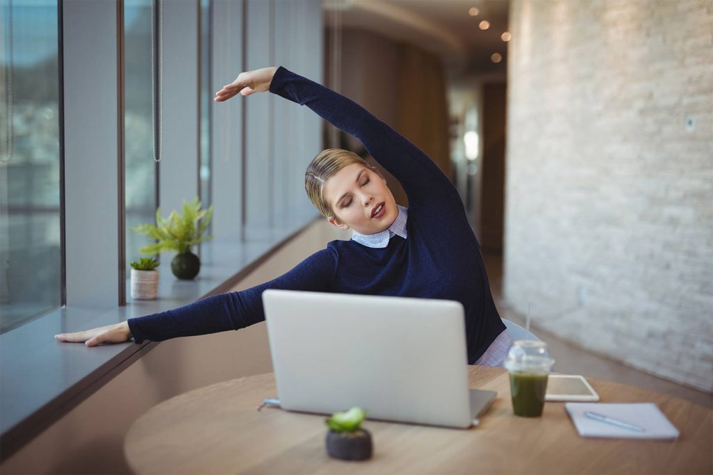 Working millennial stretching at desk