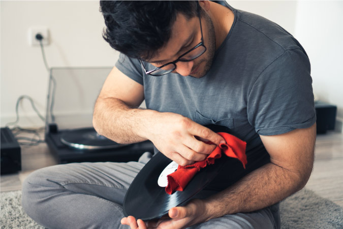 A man is using a microfiber cloth to clean a vinyl record.