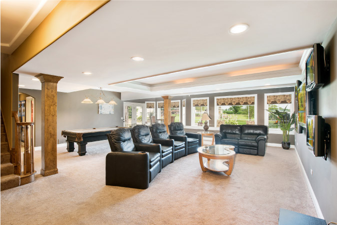  A large finished basement featuring carpeted floors, large windows, a billiards table, and theater seating. 