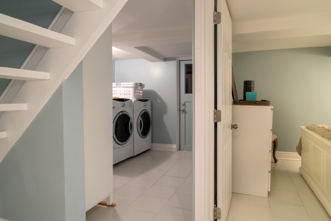 A finished basement featuring a new laundry room separated from a basement living space. 