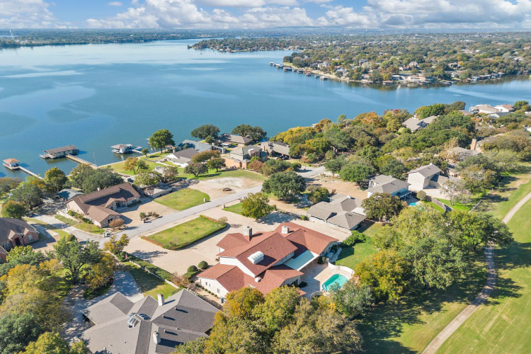 Aerial view of a residential area in DeCordova, Texas, right on a lake. It appears every bit of shoreline was built on, and many of the waterfront homes feature private docks. 