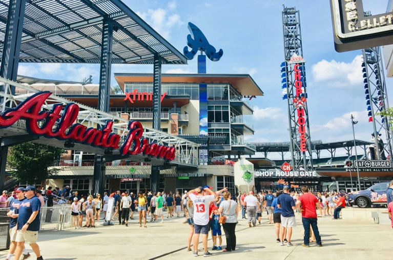 Crowds of people are walking around outside a stadium in Atlanta before a Braves game.