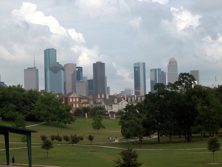 The Houston skyline seen in the distance from a nearby park, with a row of residential townhomes in between