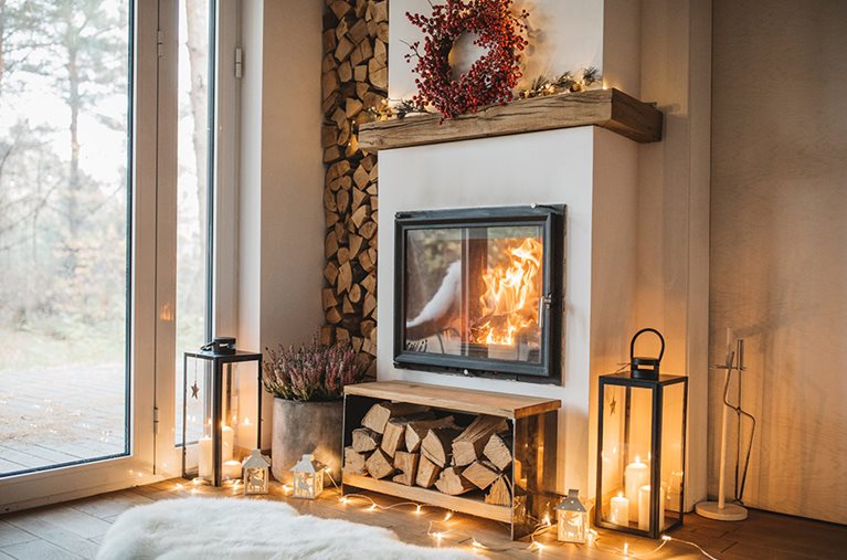 A mix of modern and classic fireplace design elements - a wood fireplace built into the chimney, with candles in glass lanterns surrounding.