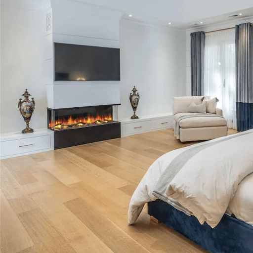 A smart fireplace sits in a bedroom with wooden floors and cream bedding