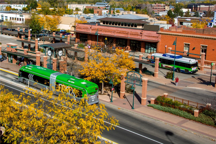 Aerial view of a street in Fort Collins where both MAX Rapid Transit and Transfort bus services are stopped to pick up passengers. 