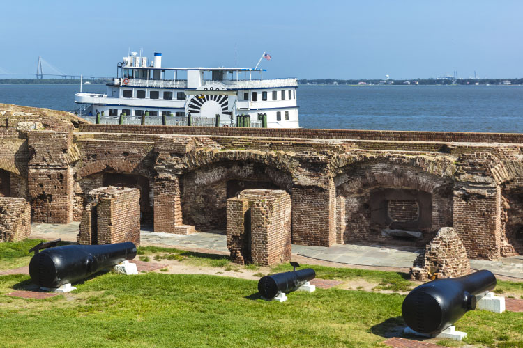 Cannons are on display behind the wall of Fort Sumter in Charleston, South Carolina, as the Spirit of the Lowcountry tour boat passes in the distance.