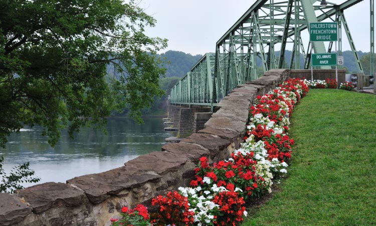 A scenic view of the Uhlerstown-Frenchtown Bridge in Frenchtown, New Jersey, spanning across the tranquil Delaware River.