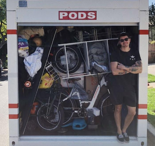 A happy PODS customer is standing in the doorway of his fully loaded PODS portable moving container