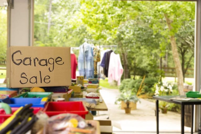 The scenes of a garage sale, including signage on cardboard and clothes hanging on racks