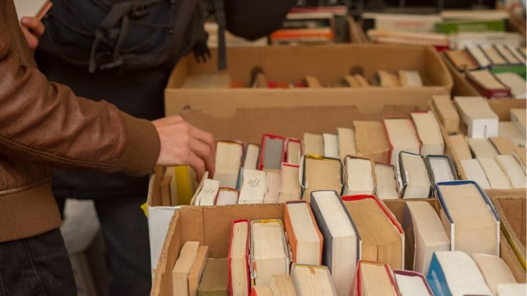 People browsing through boxes of used books at a garage sale