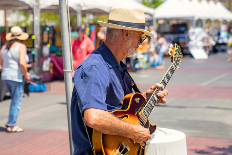 A senior man is playing electric guitar in Water Street District in Henderson, Nevada, during a local festival. 