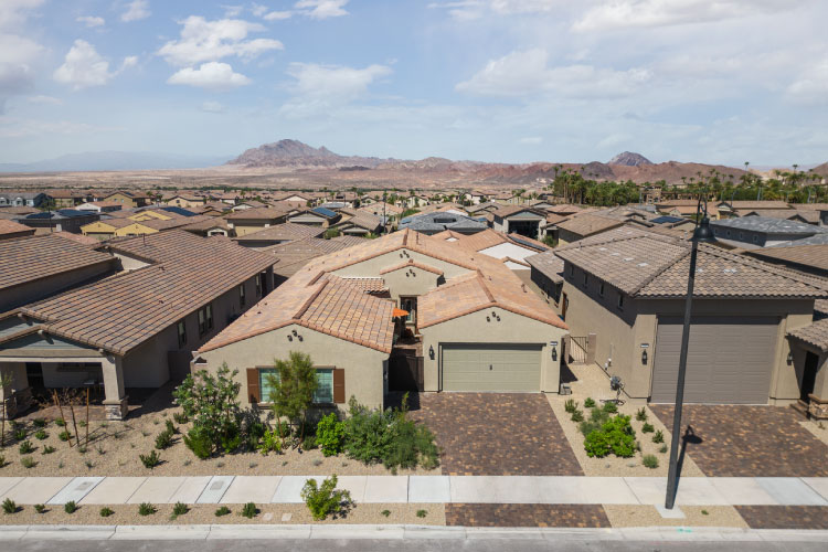 Aerial view of a residential neighborhood in Henderson, Nevada. The yards are filled with gravel, and the mountains are visible in the distance.