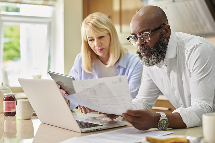 A couple is sitting together in front of a laptop, calculating their living costs for when they retire in Tennessee.