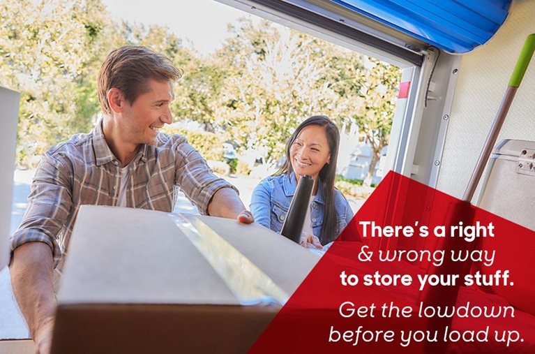 A mature couple are smiling at each other while placing boxes and furniture inside a PODS portable storage container. The overlaid text reads, “There’s a right & wrong way to store your stuff. Get the lowdown before you load up.”
