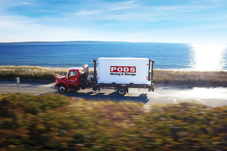 A PODS container on a truck along a scenic oceanfront highway.