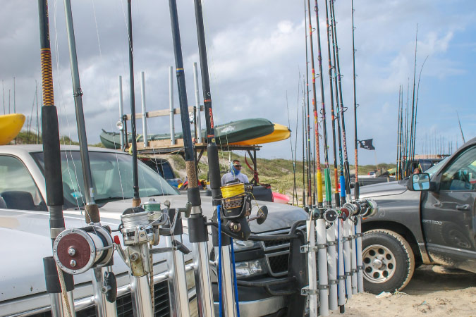 Trucks are lined up on the beach in Corpus Christi, Texas, each equipped with specialized front grills to hold half a dozen fishing rods.