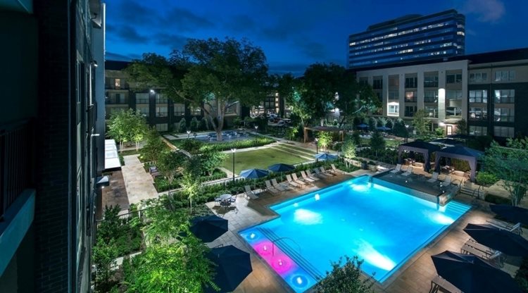 View from above of the community pool at Everra Midtown Park apartments in Dallas, TX. The apartments have a vibrant green area and a pool.