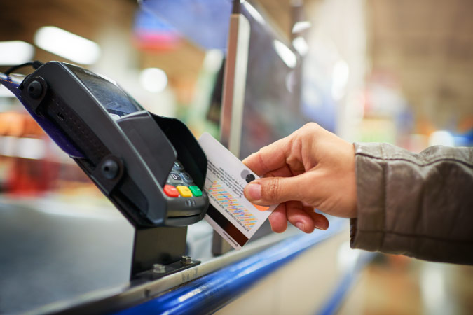 Close-up view of a person using a credit card to pay for something at a store counter.