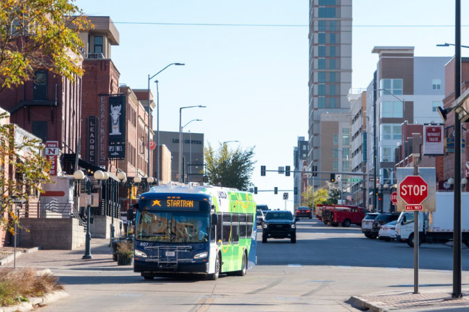 A Lincoln Startran bus drives through the city on a sunny day.