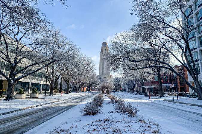 A snowy city street in Lincoln, Nebraska, in the winter with the Capitol visible in the distance.
