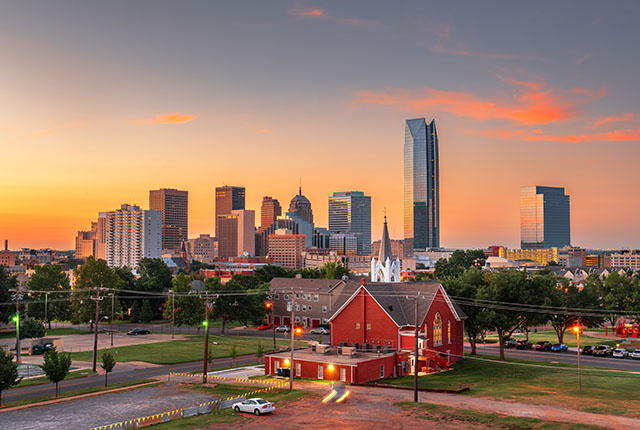The evening skyline of Oklahoma City, with a red brick church in the foreground.