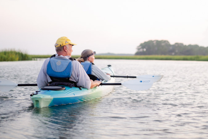 A senior couple rests their paddles to enjoy the view while kayaking on Kiawah Island in South Carolina. 