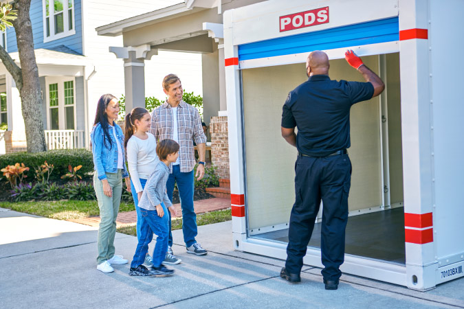  A family of four watches on excitedly as their PODS driver opens the blue door of their portable storage container so they can begin their moving journey. 