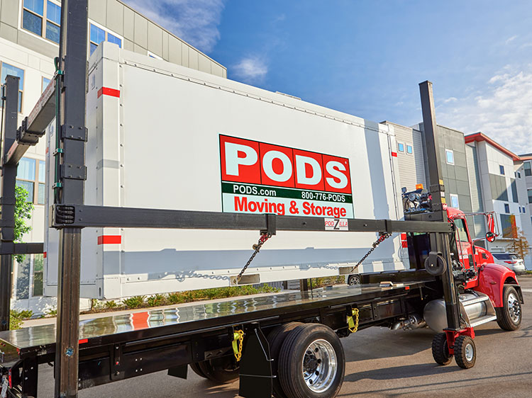 A PODS container loaded up on a truck by PODZILLA. The truck is parked in an apartment complex.