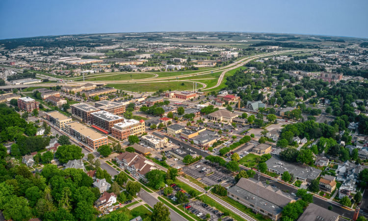 Aerial view of the Madison suburb of Middleton, Wisconsin, in the summer. The sky is a clear blue, and there are many large, mature trees throughout the community, bushy with green leaves