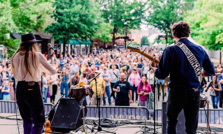 A view from upstage of a live performance and a riveted audience on Main Street in Greenville, South Carolina