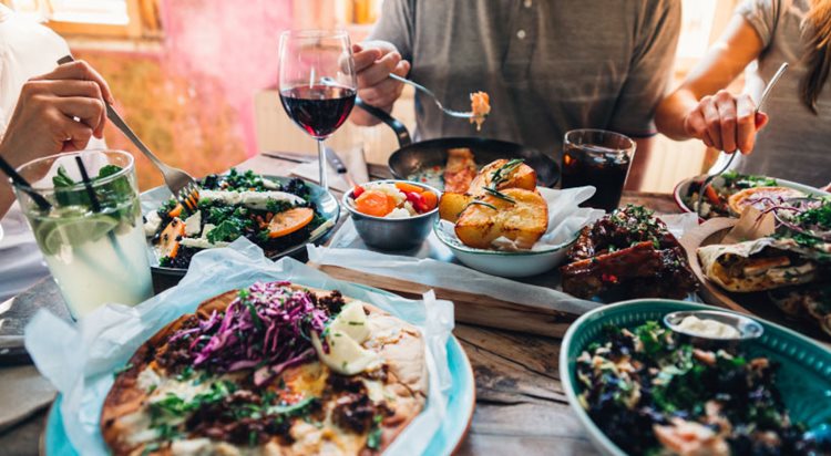 Close-up view of a restaurant table filled with delicious-looking Mediterranean cuisine, cocktails, and other drinks