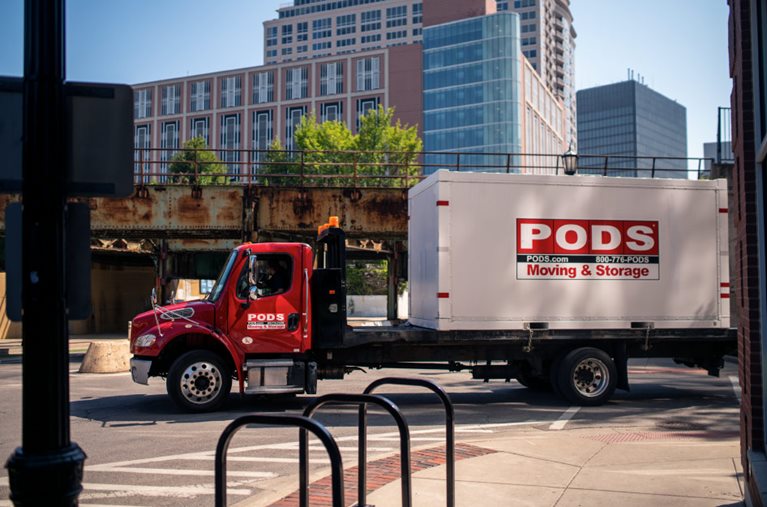 A PODS truck is transporting a PODS portable moving and storage container through the city streets of Chicago with a final destination of Addison, Illinois.