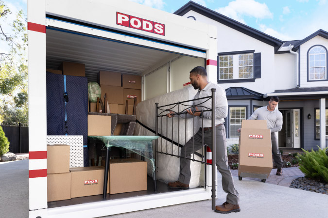 Two movers help to load a PODS portable moving container after being hired as local packing and loading assistance through PODS.