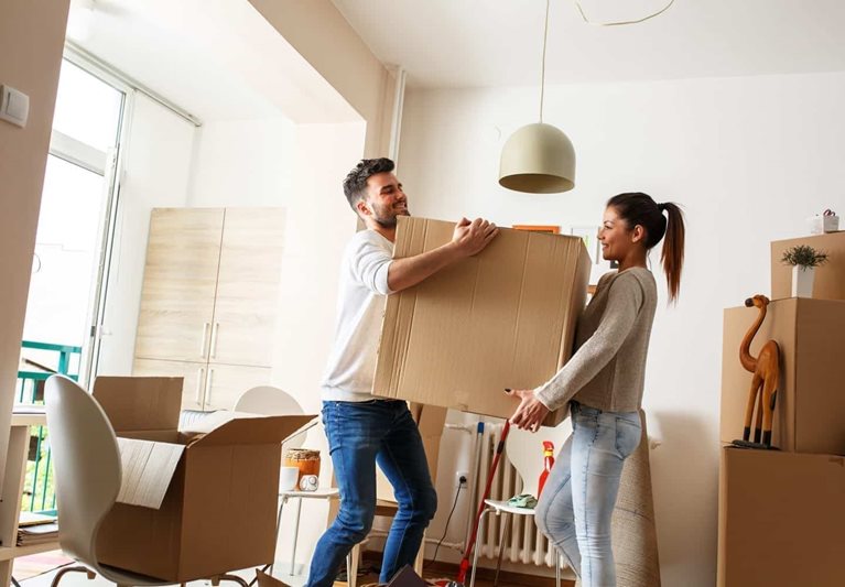 A young couple moving boxes into their new home
