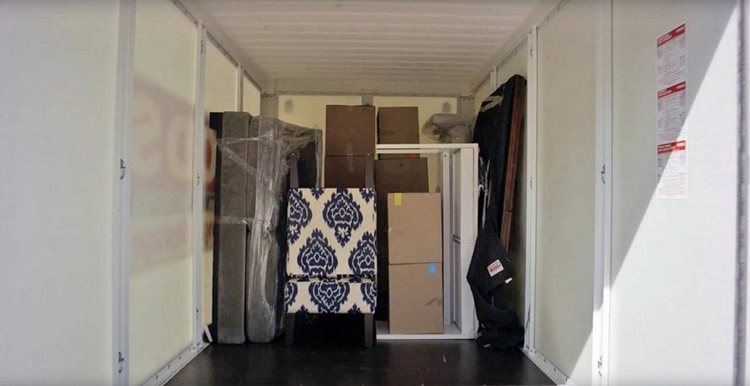 The interior of a PODS Container filled with a table, couch, and various other furniture items. 