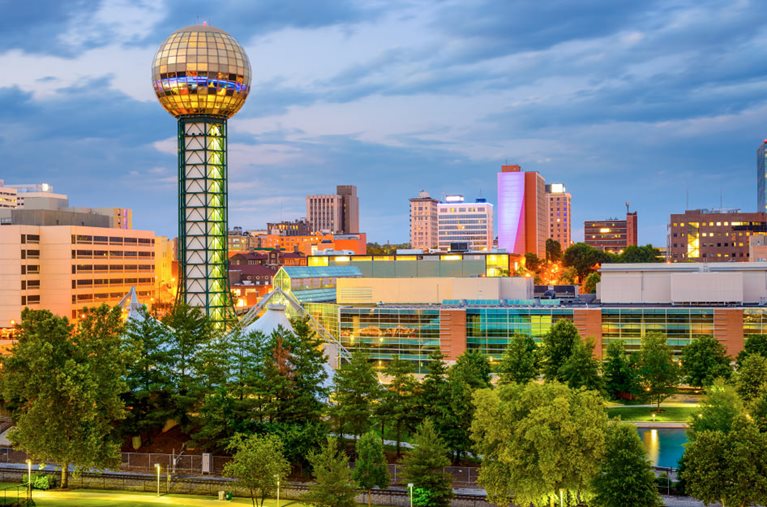 The Knoxville, Tennessee, skyline with downtown buildings, the Sunsphere, and World’s Fair Park at sunset.