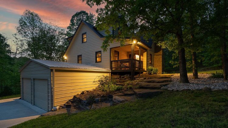 A two-story home in Nashville, Indiana, built into a hill in the woods with a covered porch on the second level.