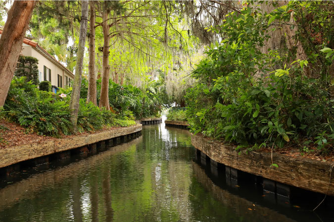 View down a channel in Winter Park’s Chain of Lakes Canal with a residential house high on the banks to the left