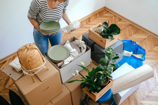 A soldier in civilian attire is packing up moving boxes during her partial DITY move.