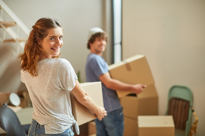 A military couple is carrying moving boxes as they prepare for their partial DITY move.