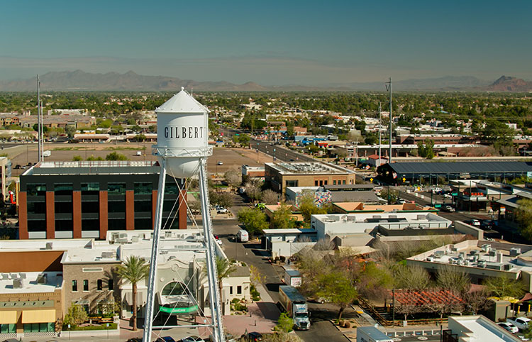 Gilbert’s water tower stands tall in the foreground above the highways below. Businesses line the street.