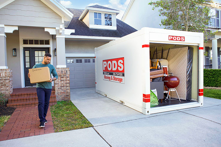 A man loading a box labeled “bedroom” into a ӰPro container