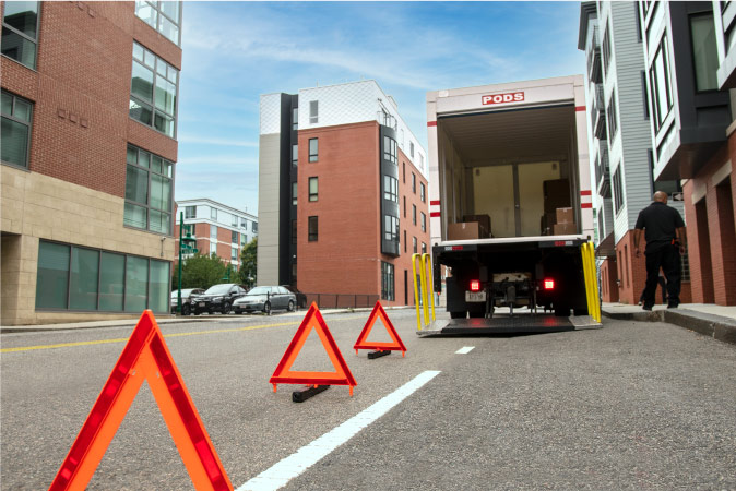 A driver waits beside a partially loaded PODS moving container while the customer is in between loading trips.