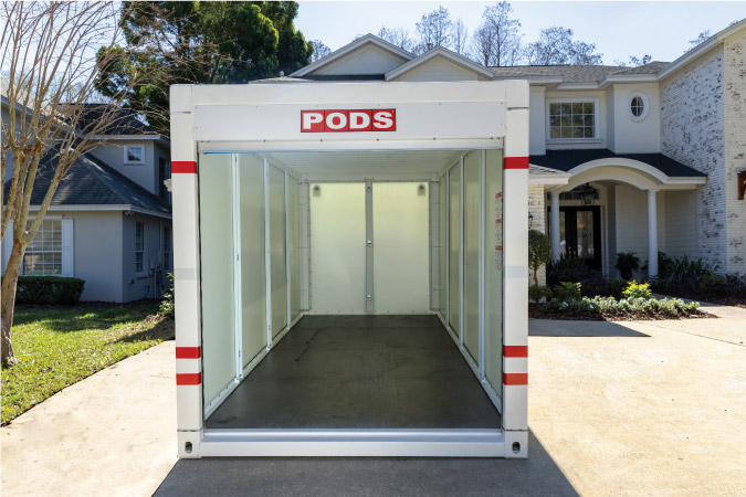 View of the inside of an empty PODS container, positioned in the driveway of a large residential home.