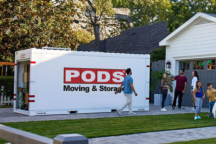 A man walks toward his family, away from his loaded PODS container